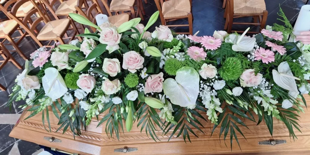 Dessus de cercueil composé de roses roses et de lys blancs.