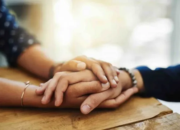 Deux personnes se tenant la main en signe de soutien et d'empathie.