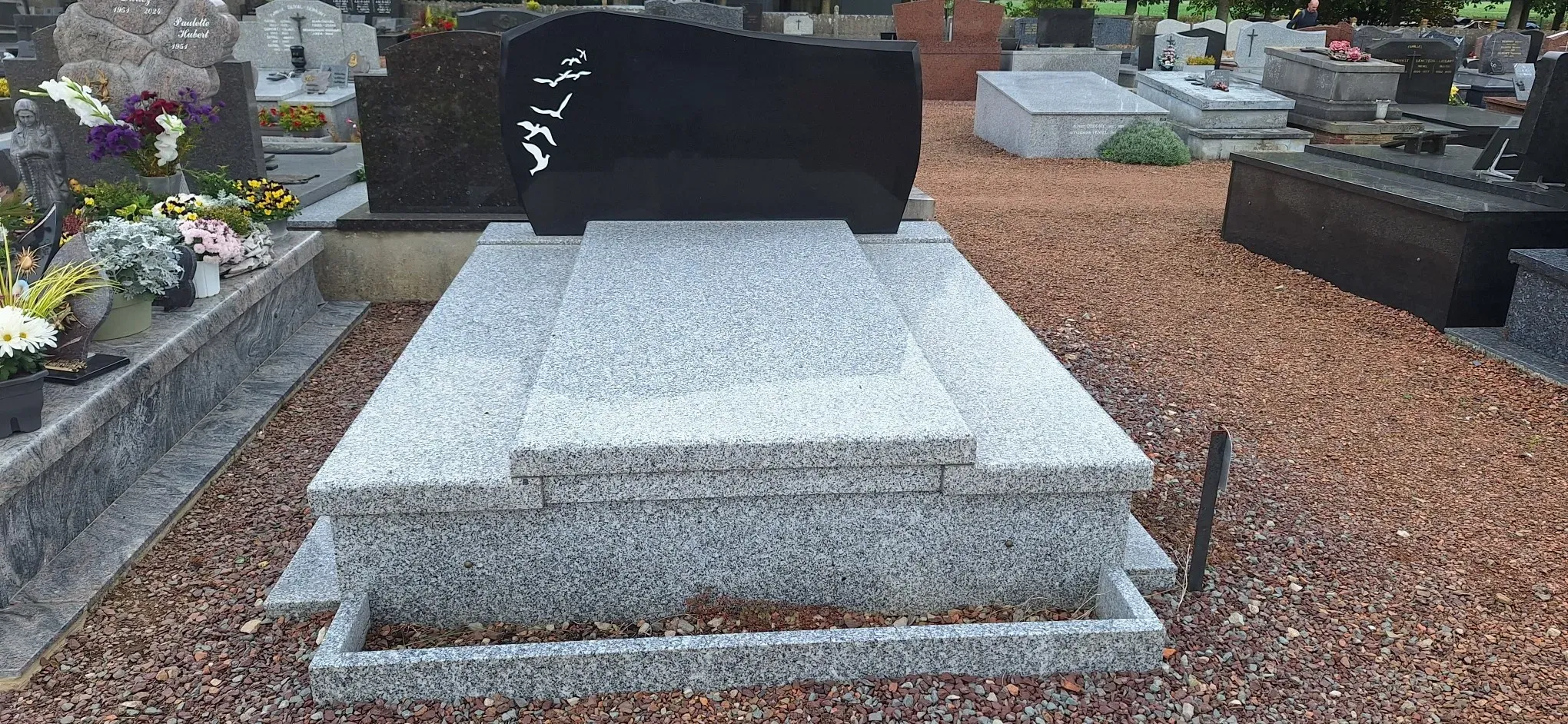 Gros plan sur un monument funéraire bicolore avec gravure d'oiseaux.