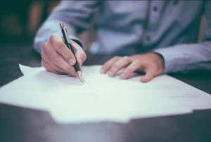 Gros plan sur une main signant un contrat de prévoyance avec un stylo.
